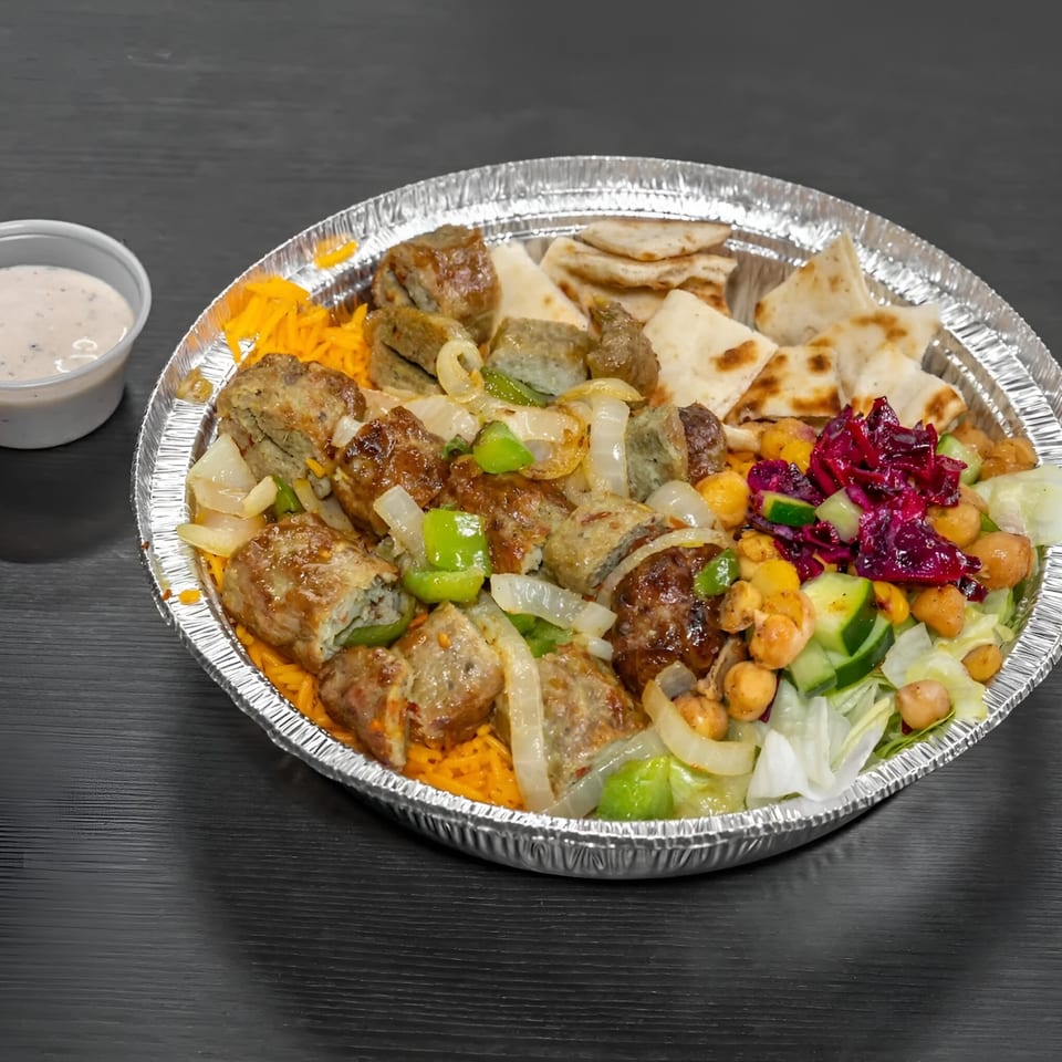 Halal platter with meat, rice, pita, salad, chickpeas, and a side of white sauce.