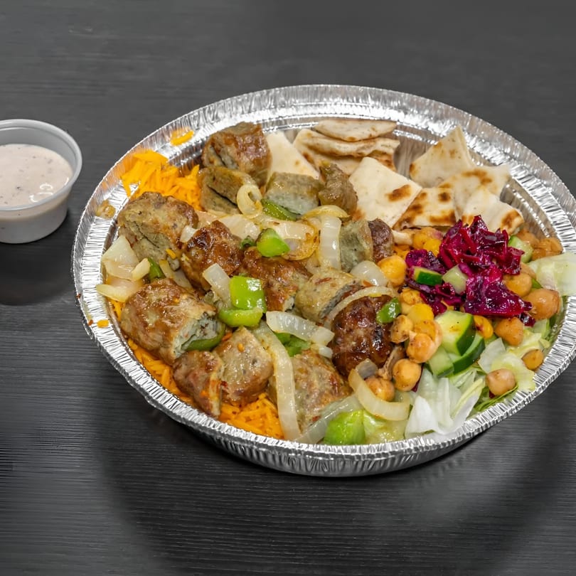 Halal platter with meat, rice, pita, salad, chickpeas, and a side of white sauce.